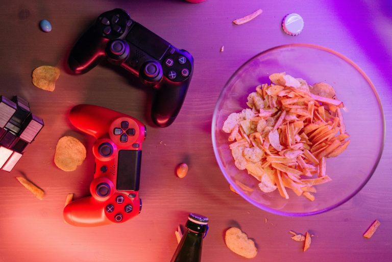 Overhead view of game controllers and snacks on a table, perfect for a gaming night setup.